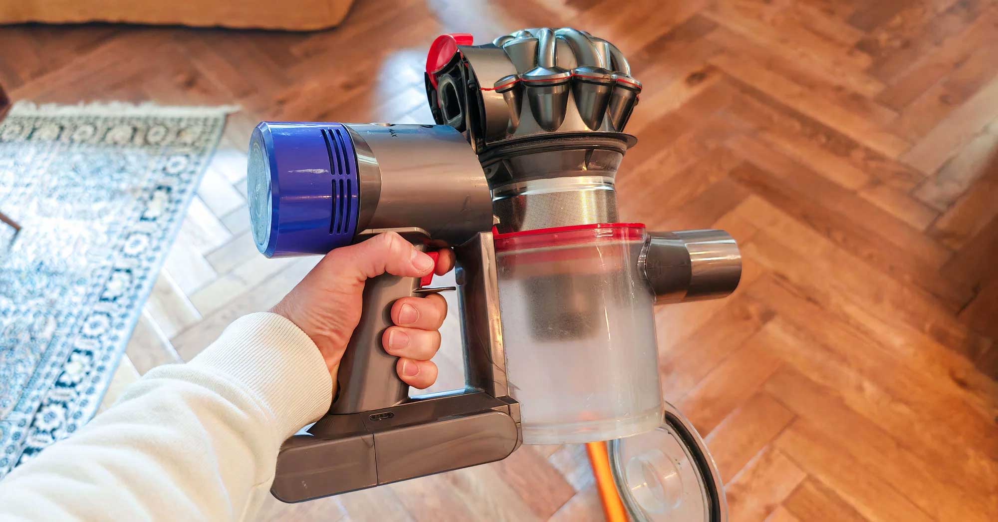 Système de vidange du Dyson V8 : il suffit de tirer un taquet rouge sur le dessus. Le bloc moteur remonte et le clapet du bas s'ouvre. Un joint glisse le long du bloc de filtration pour expulser la poussière vers le bas. (c) Labo Maison