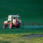 Tracteur pulvérisant des pesticides sur un champ agricole en pleine journée